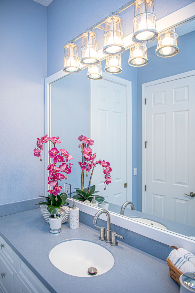 На фото: главная ванная комната среднего размера в современном стиле с фасадами в стиле шейкер, белыми фасадами, угловой ванной, душем над ванной, унитазом-моноблоком, синими стенами, подвесной раковиной, синей столешницей, тумбой под одну раковину и встроенной тумбой