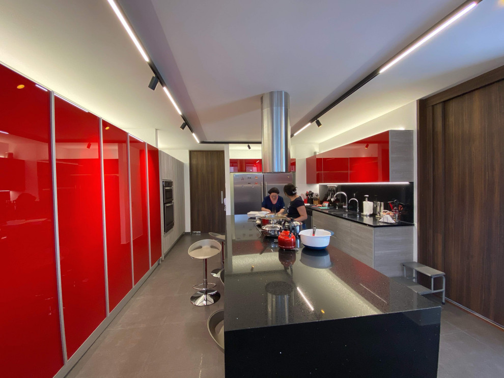 Photo of a large modern u-shaped kitchen/diner with a submerged sink, flat-panel cabinets, red cabinets, granite worktops, black splashback, stone tiled splashback, stainless steel appliances, porcelain flooring, an island, black floors, black worktops and a coffered ceiling.