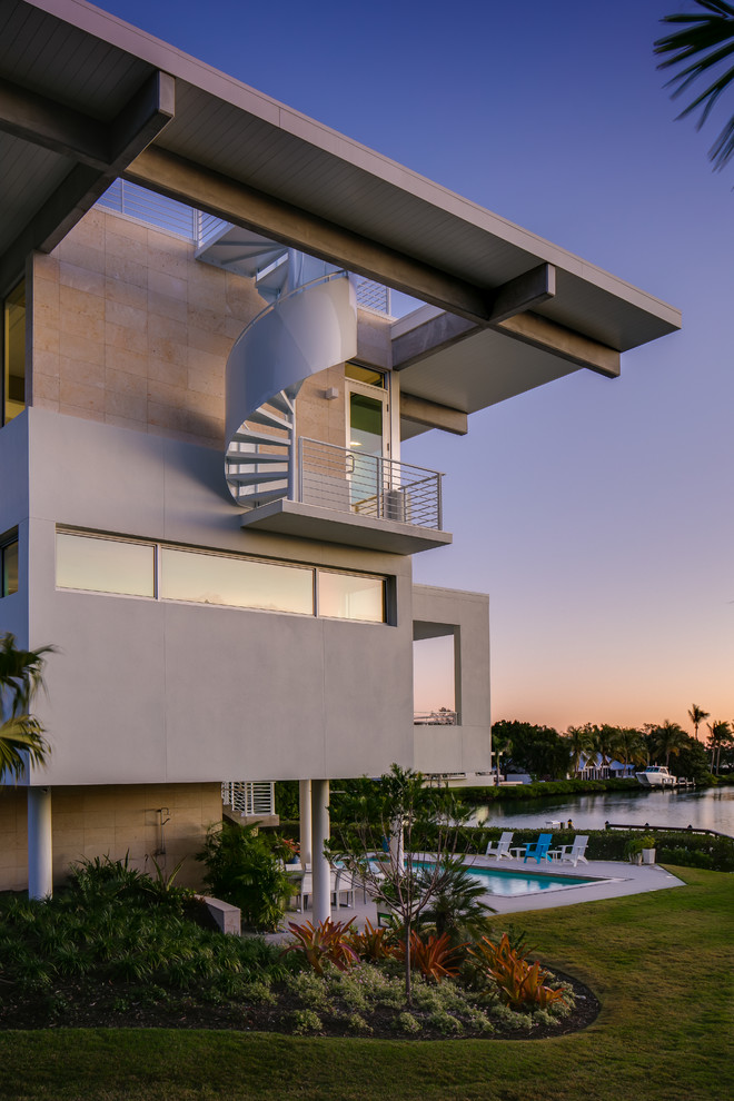 Photo of a large contemporary three-storey white house exterior in Tampa with stone veneer, a flat roof and a metal roof.