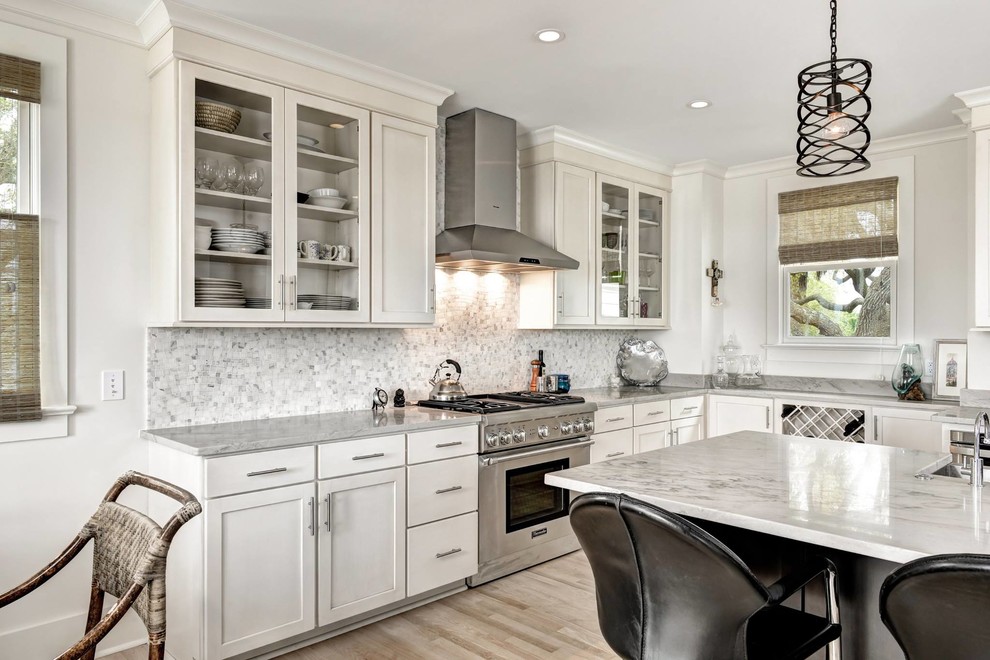 Mid-sized traditional l-shaped separate kitchen in Charleston with a farmhouse sink, shaker cabinets, white cabinets, marble benchtops, white splashback, mosaic tile splashback, stainless steel appliances, light hardwood floors and with island.