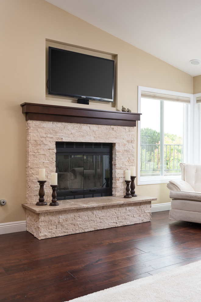 Photo of an expansive traditional open concept family room in San Diego with beige walls, dark hardwood floors, a standard fireplace, a wall-mounted tv, a stone fireplace surround and brown floor.