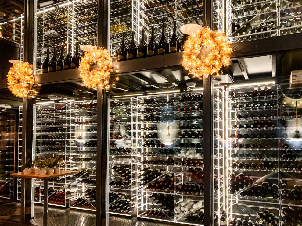 This is an example of an expansive modern wine cellar in San Francisco with laminate floors, storage racks and black floor.