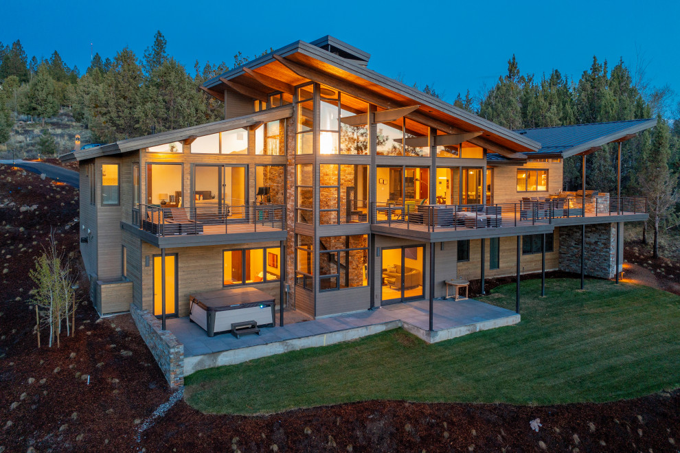 На фото: большой, двухэтажный, коричневый частный загородный дом в стиле ретро с крышей-бабочкой, металлической крышей и отделкой планкеном с