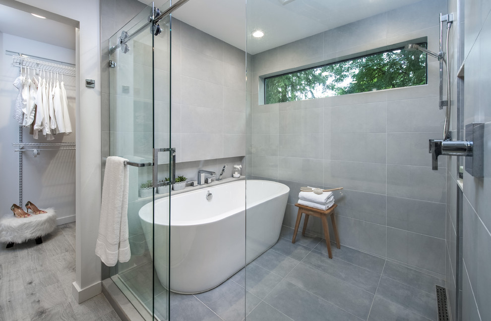 This is an example of a large transitional master bathroom in Seattle with flat-panel cabinets, grey cabinets, a freestanding tub, an open shower, a one-piece toilet, white tile, stone slab, blue walls, light hardwood floors, a drop-in sink and solid surface benchtops.