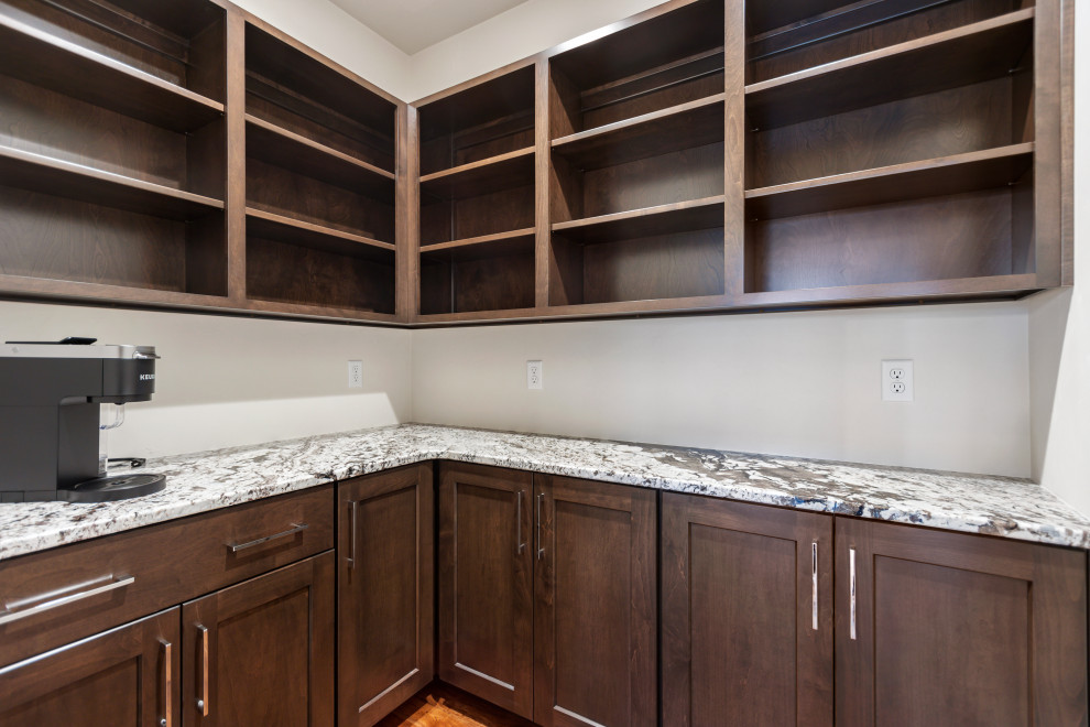 This is an example of a mid-sized transitional l-shaped kitchen pantry in Other with shaker cabinets, dark wood cabinets, granite benchtops, medium hardwood floors, no island, brown floor and multi-coloured benchtop.