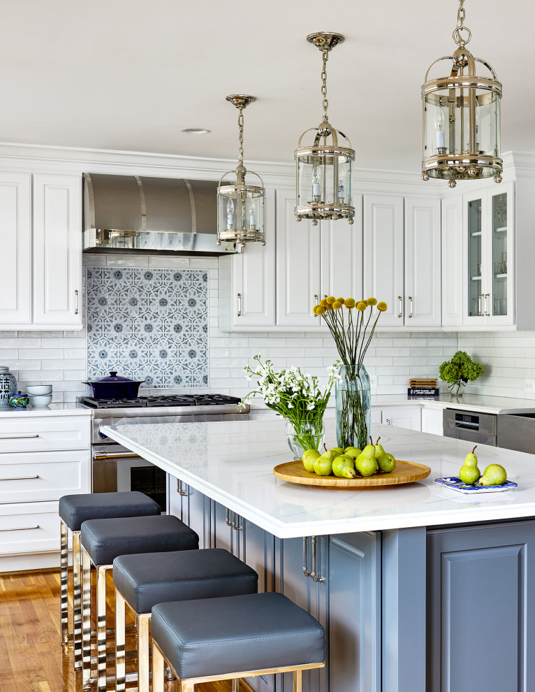 Inspiration for a mid-sized transitional l-shaped kitchen in DC Metro with a farmhouse sink, raised-panel cabinets, white cabinets, quartz benchtops, white splashback, subway tile splashback, stainless steel appliances, medium hardwood floors, brown floor and white benchtop.