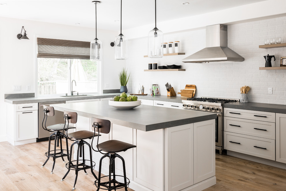 Inspiration for a country kitchen in Orange County with an undermount sink, shaker cabinets, white cabinets, white splashback, subway tile splashback, stainless steel appliances, medium hardwood floors, with island, brown floor and grey benchtop.