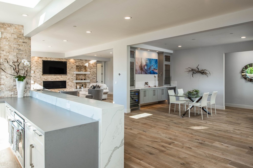 Mid-sized transitional light wood floor great room photo in Orange County with gray walls, a ribbon fireplace and a stone fireplace