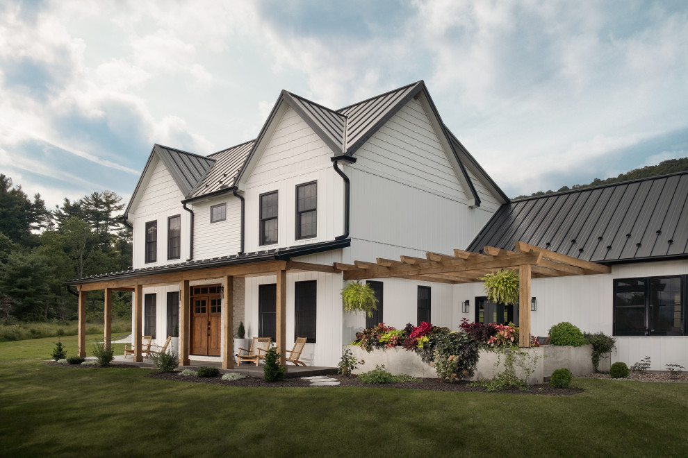 Foto de fachada de casa blanca y negra campestre grande de dos plantas con revestimiento de vinilo, tejado a dos aguas, tejado de metal y panel y listón