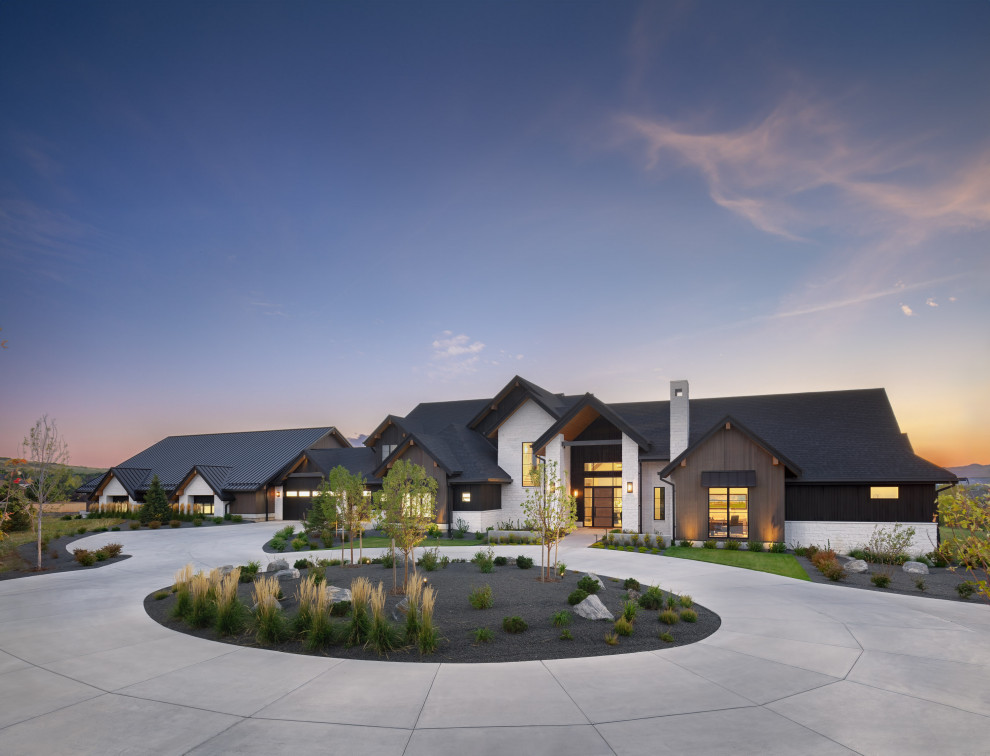 Award-Winning Luxury Custom Home | Modern + Traditional Interior Design | Lone T - The front entry of this luxury custom home is striking, with traditional roofline and modern materials on the facade. White stone, light wood paneling, black steel awnings, and a grand steel and wood door framed in windows.