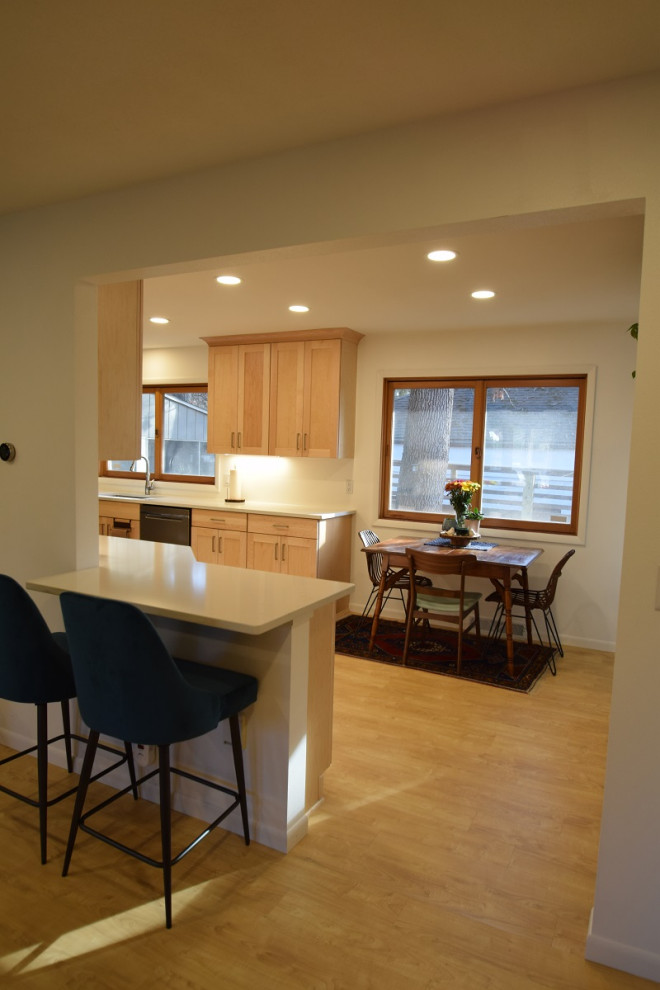 Galley vinyl floor kitchen photo with an undermount sink, shaker cabinets, light wood cabinets, quartz countertops, stainless steel appliances and white countertops