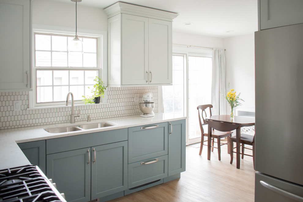 Inspiration for a mid-sized transitional l-shaped light wood floor and beige floor eat-in kitchen remodel in Chicago with an undermount sink, shaker cabinets, quartz countertops, white backsplash, mosaic tile backsplash, stainless steel appliances, no island, white countertops and blue cabinets