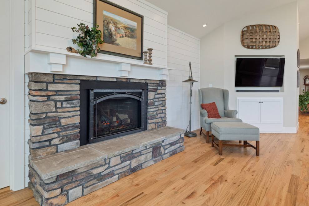 Design ideas for a large country formal open concept living room in Other with white walls, medium hardwood floors, a standard fireplace, a stone fireplace surround, a wall-mounted tv, multi-coloured floor, vaulted and planked wall panelling.