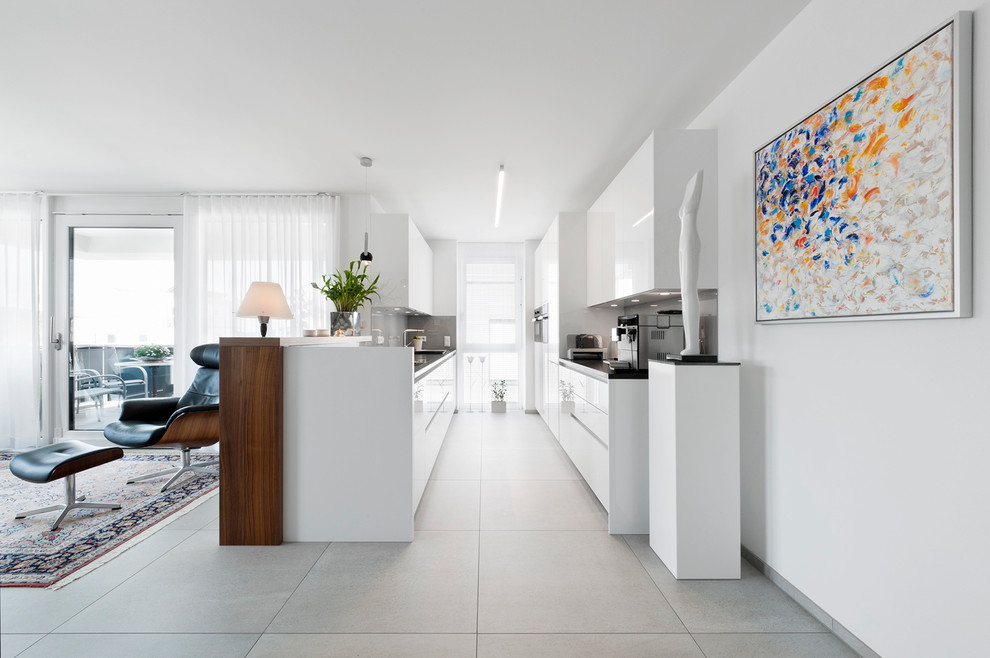 Contemporary galley kitchen in Stuttgart with an integrated sink, flat-panel cabinets, white cabinets, granite benchtops, grey splashback, stone slab splashback, stainless steel appliances and no island.