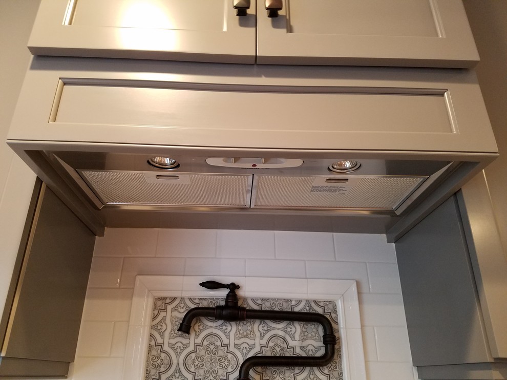 Example of a mid-sized transitional galley light wood floor and brown floor eat-in kitchen design with a farmhouse sink, recessed-panel cabinets, gray cabinets, wood countertops, white backsplash, subway tile backsplash, stainless steel appliances and an island