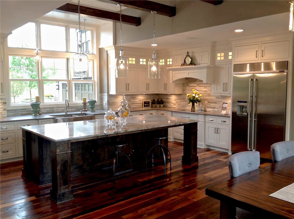 Large transitional l-shaped medium tone wood floor and brown floor open concept kitchen photo in Cedar Rapids with a farmhouse sink, shaker cabinets, white cabinets, granite countertops, beige backsplash, limestone backsplash, stainless steel appliances and an island
