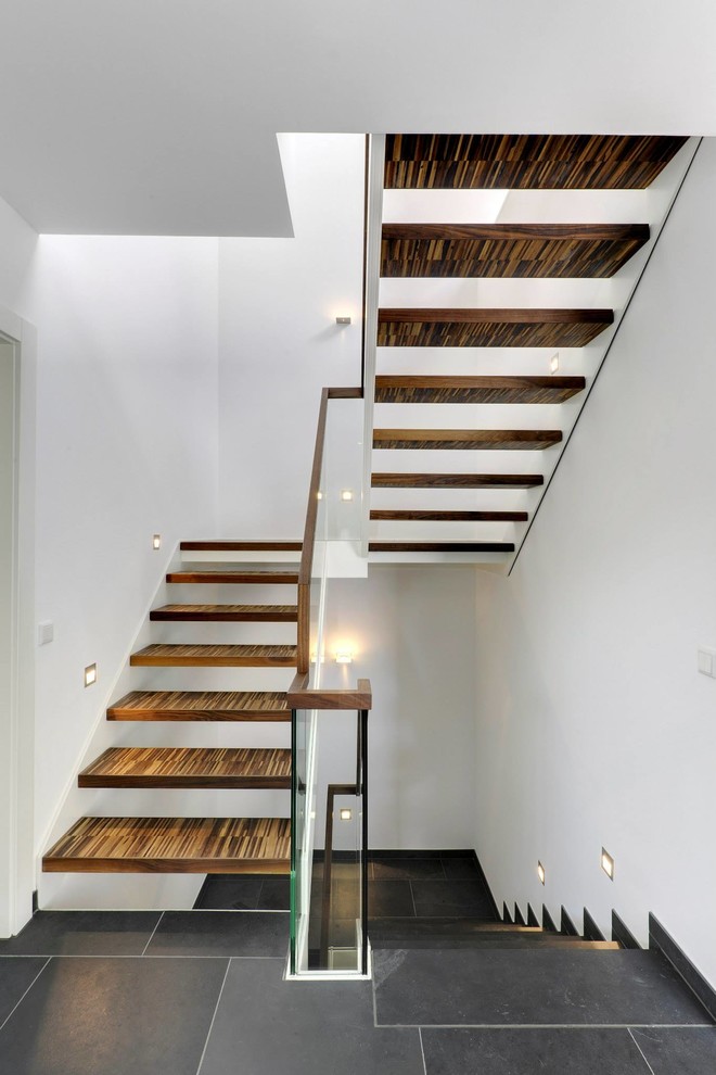 This is an example of a mid-sized modern wood u-shaped staircase in Essen with open risers.