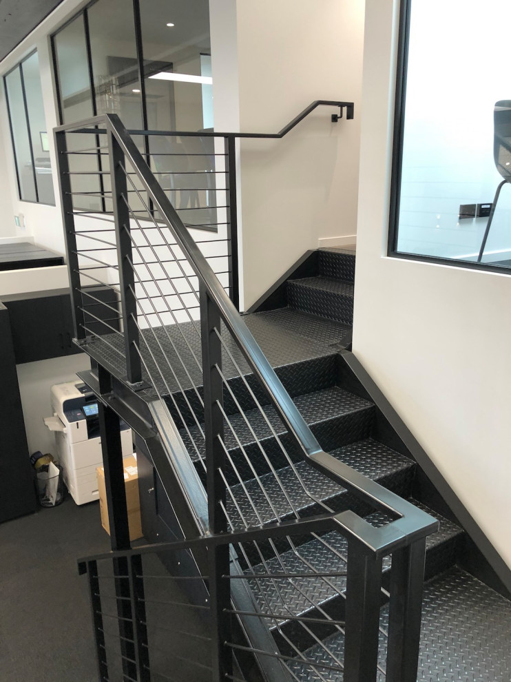 Example of a large urban metal u-shaped metal railing staircase design in Auckland with metal risers