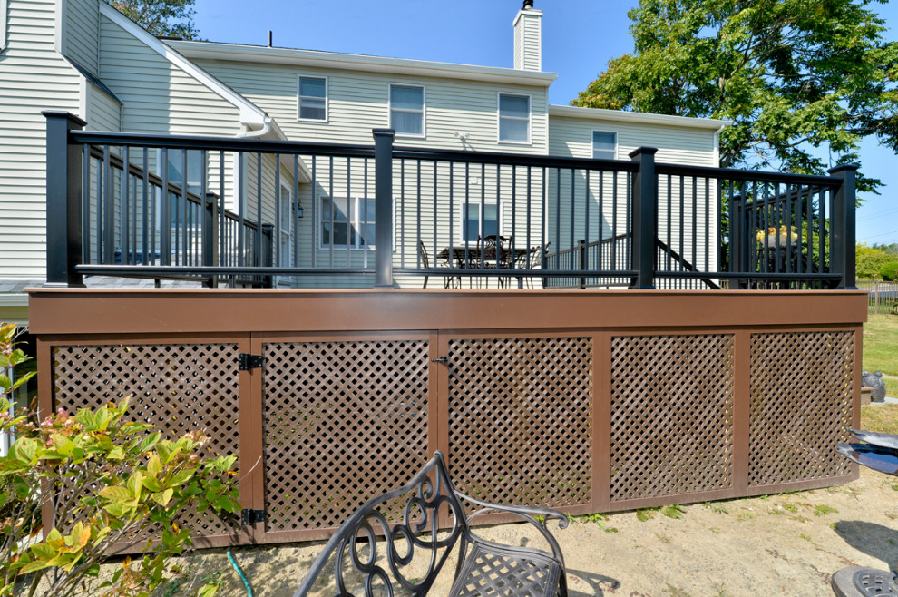 Mid-sized contemporary backyard and ground level deck in New York with no cover and metal railing.