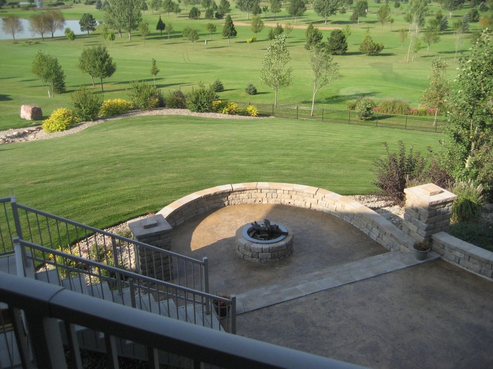 Example of a large transitional backyard stamped concrete patio design with a fire pit and no cover