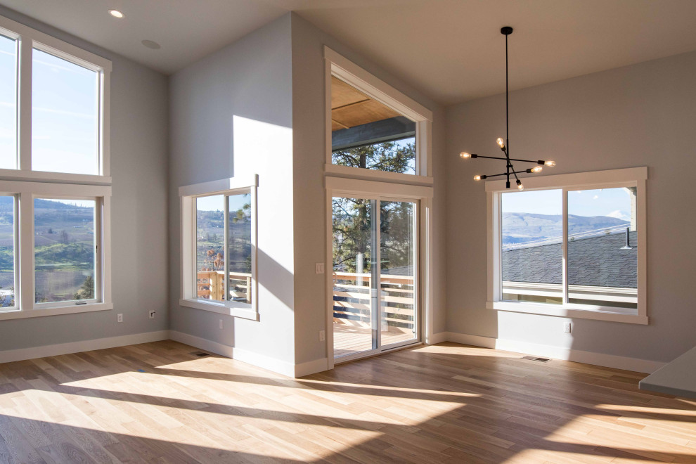 Cette image montre une salle à manger ouverte sur le salon minimaliste de taille moyenne avec un mur gris, parquet clair, une cheminée standard et un plafond voûté.