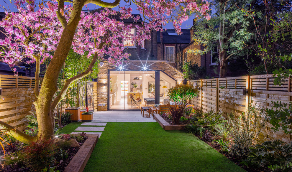 Design ideas for a contemporary partial sun garden in London with a wood fence.