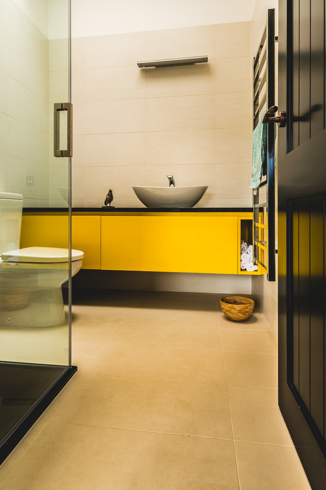 Inspiration for a mid-sized contemporary master bathroom in Auckland with flat-panel cabinets, yellow cabinets, a corner shower, a two-piece toilet, beige tile, beige walls, a vessel sink, solid surface benchtops, beige floor, a hinged shower door, ceramic tile and ceramic floors.