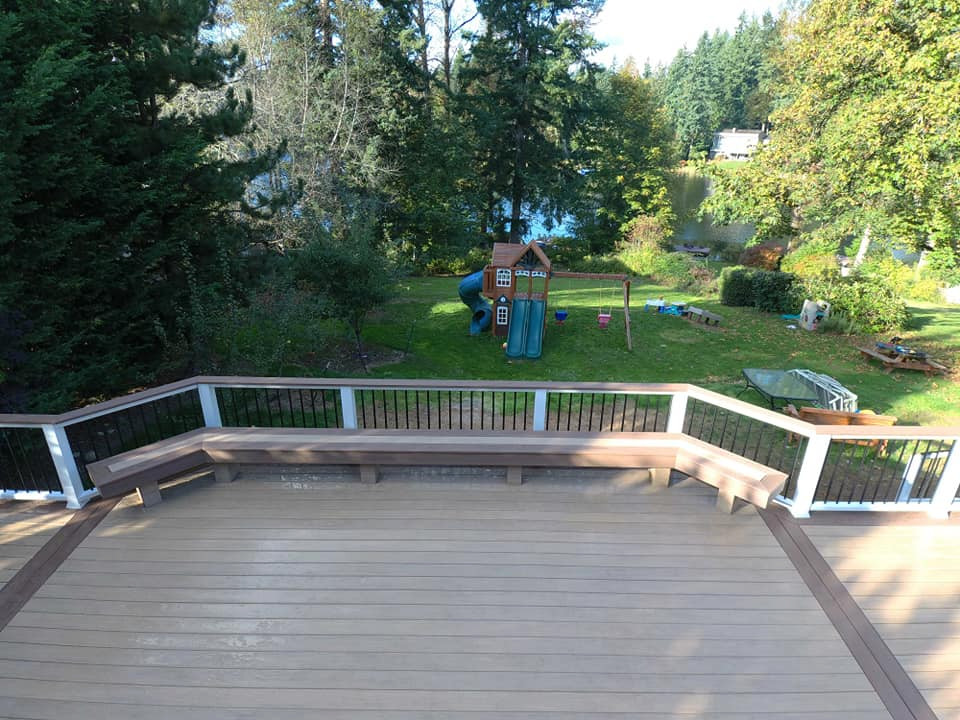 Expansive beach style backyard deck in Seattle with a pergola.