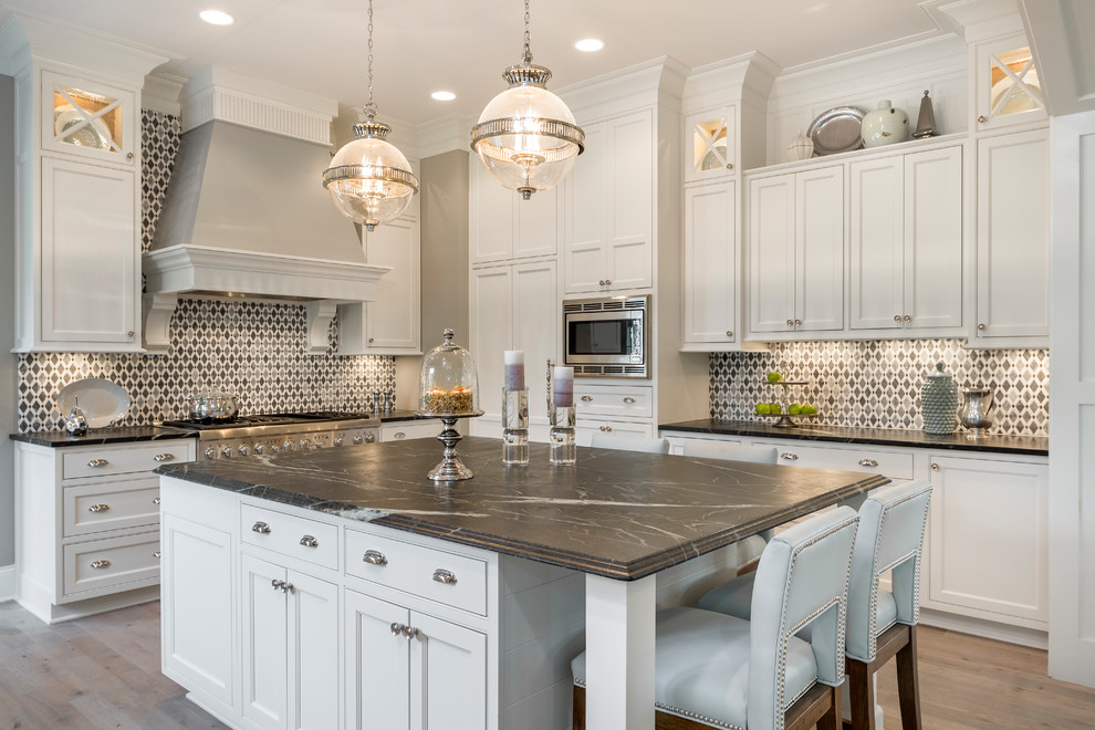 Traditional kitchen in Cincinnati with beaded inset cabinets, white cabinets, multi-coloured splashback, stainless steel appliances, light hardwood floors, with island and beige floor.