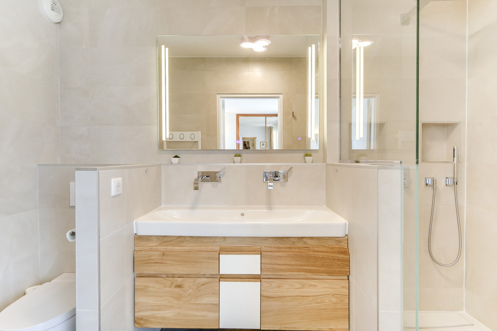 Inspiration for a mid-sized contemporary 3/4 bathroom in Paris with beaded inset cabinets, light wood cabinets, an open shower, a wall-mount toilet, beige tile, ceramic tile, beige walls, ceramic floors, a console sink, beige floor, an open shower and white benchtops.