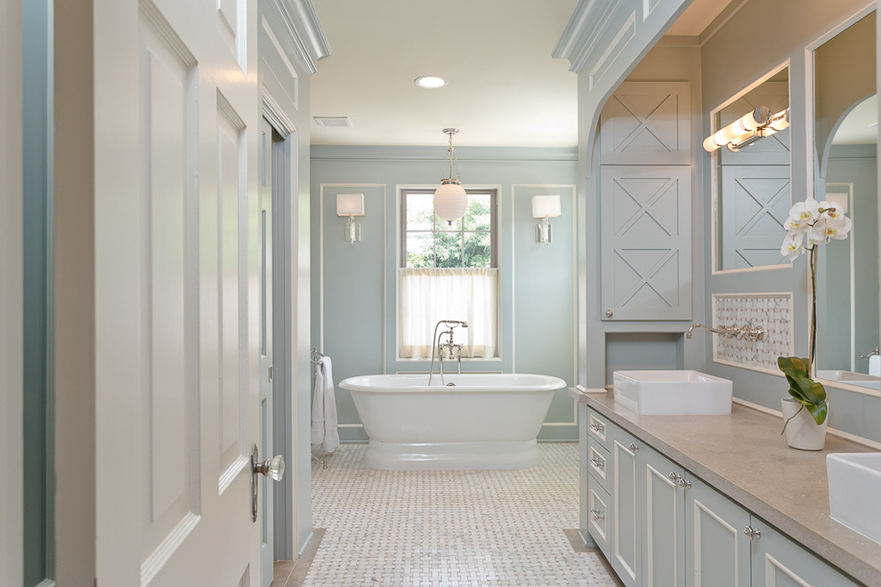 Inspiration for a mid-sized transitional master bathroom in Houston with a vessel sink, recessed-panel cabinets, blue cabinets, limestone benchtops, a freestanding tub, an alcove shower, a two-piece toilet, blue tile, mosaic tile, blue walls and marble floors.