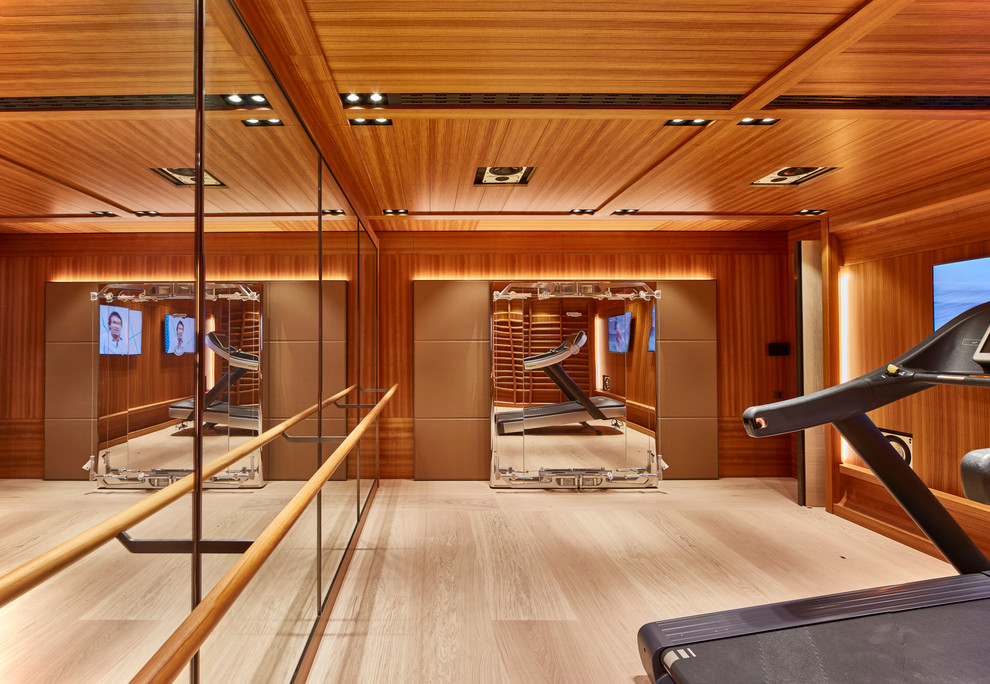 This is an example of an expansive contemporary multipurpose gym in London with brown walls and light hardwood floors.