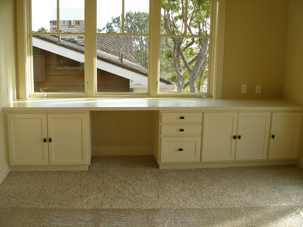 This is an example of a mid-sized traditional study room in San Diego with yellow walls, carpet, no fireplace, a built-in desk and beige floor.