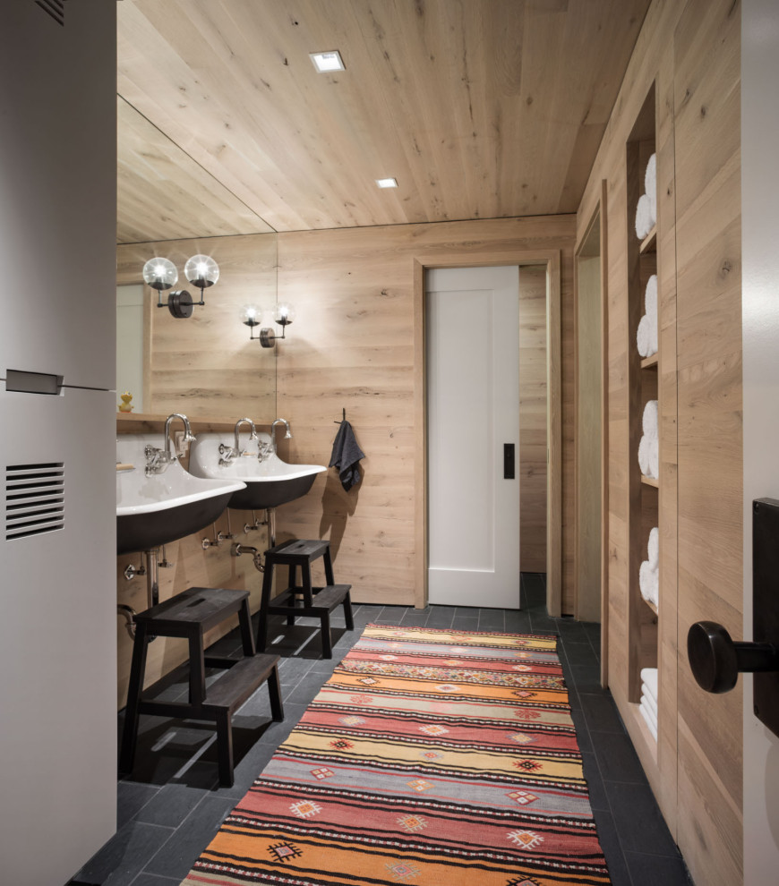 This is an example of a transitional kids wet room bathroom in Portland Maine with dark wood cabinets, a one-piece toilet, slate floors, a wall-mount sink, wood benchtops, black floor, a hinged shower door, a double vanity, a floating vanity and wood walls.