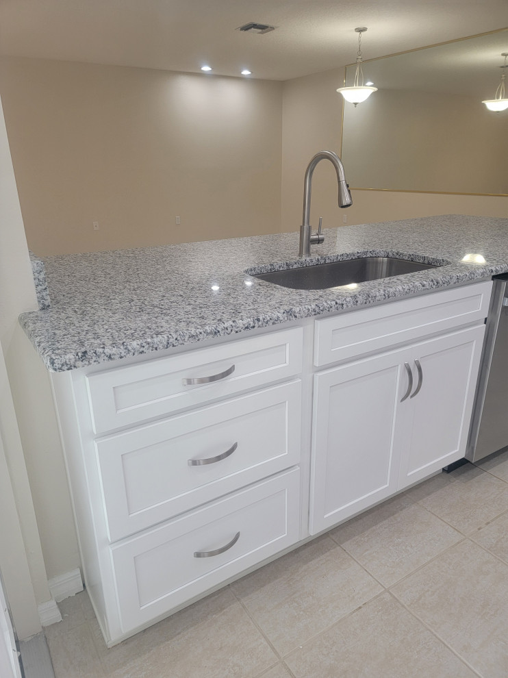 Eat-in kitchen - mid-sized galley eat-in kitchen idea with an undermount sink, shaker cabinets, white cabinets, quartz countertops, a peninsula and gray countertops
