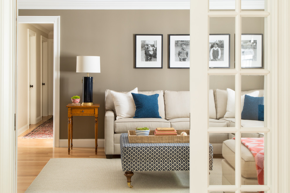 This is an example of a mid-sized traditional enclosed family room in Boston with beige walls, light hardwood floors, a wall-mounted tv and no fireplace.