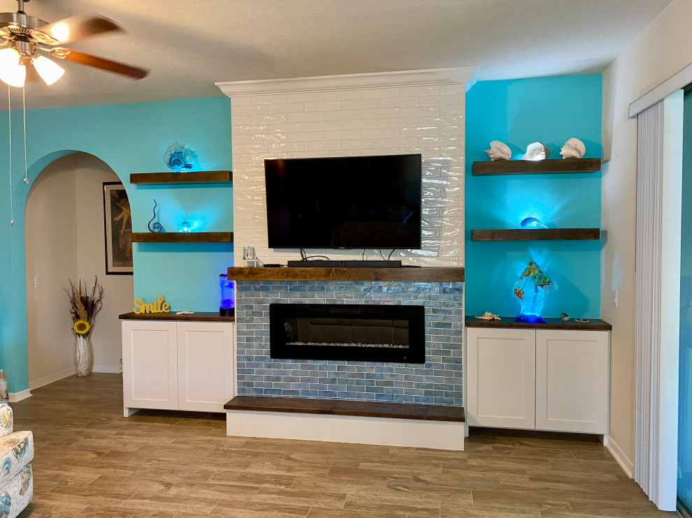 Large beach style games room in Orlando with blue walls, ceramic flooring, a hanging fireplace, a tiled fireplace surround, a built-in media unit, brown floors and wood walls.