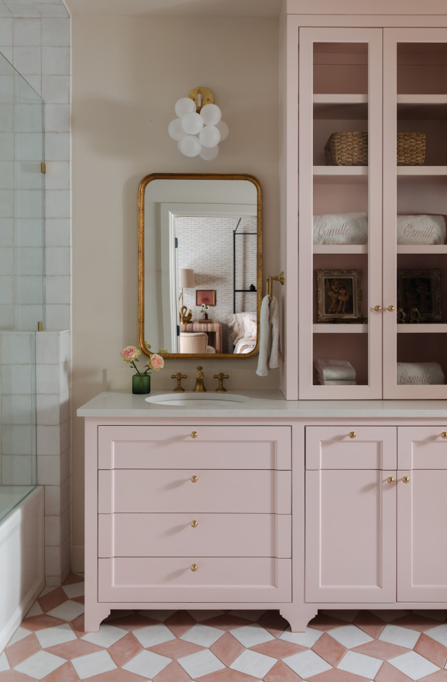 オースティンにあるトランジショナルスタイルのおしゃれな浴室 (落し込みパネル扉のキャビネット、アルコーブ型浴槽、シャワー付き浴槽	、白いタイル、ベージュの壁、アンダーカウンター洗面器、ピンクの床、グレーの洗面カウンター、独立型洗面台) の写真