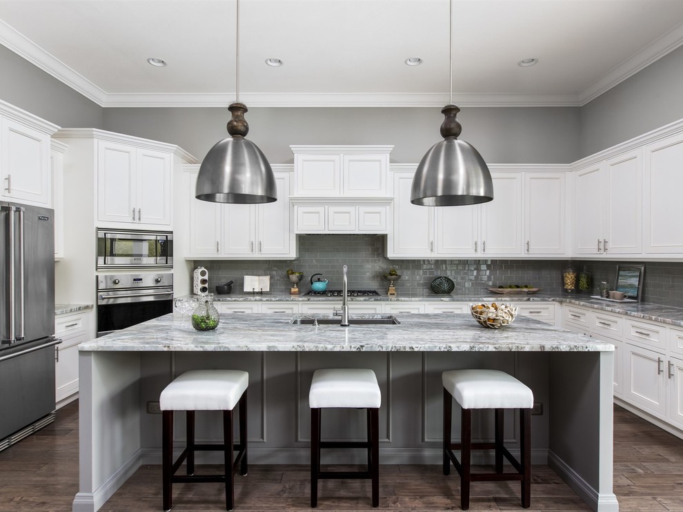 Large transitional u-shaped eat-in kitchen in Orlando with an undermount sink, recessed-panel cabinets, stainless steel cabinets, granite benchtops, grey splashback, subway tile splashback, stainless steel appliances, dark hardwood floors and with island.