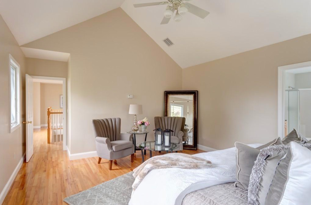 This is an example of a large traditional master bedroom in Boston with beige walls and light hardwood floors.