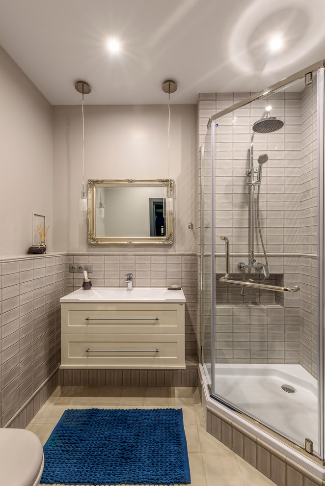 Inspiration for a mid-sized contemporary 3/4 bathroom in Other with recessed-panel cabinets, a corner shower, gray tile, grey walls, an integrated sink, a hinged shower door, grey cabinets, a wall-mount toilet, ceramic tile, porcelain floors and grey floor.