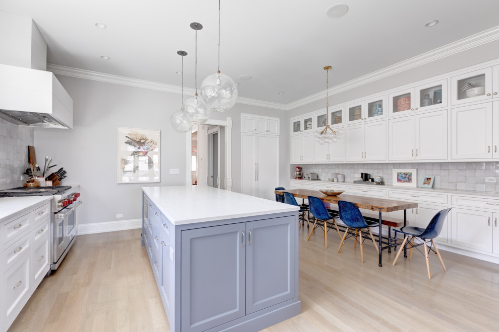 Inspiration for a transitional galley light wood floor and beige floor kitchen remodel in Chicago with shaker cabinets, white cabinets, gray backsplash, stainless steel appliances, an island and white countertops