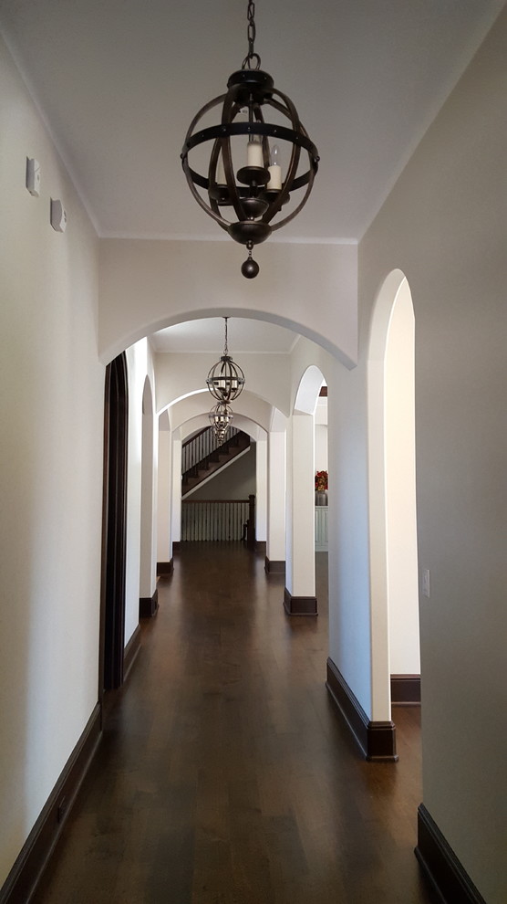 Large mediterranean hallway in New York with dark hardwood floors, white walls and brown floor.