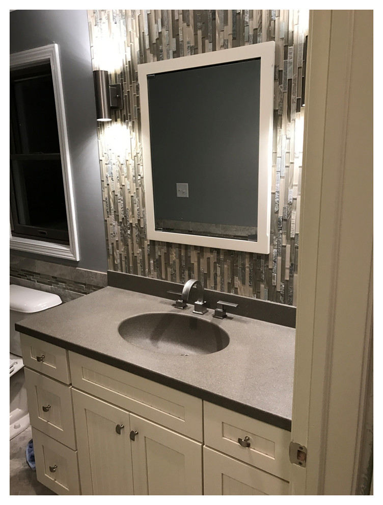 Inspiration for a mid-sized transitional master gray tile and porcelain tile porcelain tile walk-in shower remodel with recessed-panel cabinets, white cabinets, a two-piece toilet, gray walls, an integrated sink and solid surface countertops