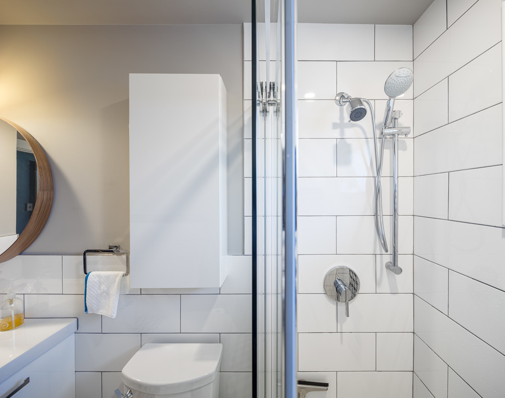 This is an example of a small contemporary bathroom in Ottawa with flat-panel cabinets, white cabinets, a double shower, a two-piece toilet, black and white tile, ceramic tile, grey walls, ceramic floors, an integrated sink and solid surface benchtops.
