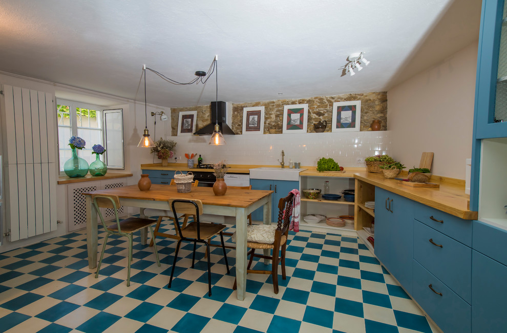 Design ideas for a mid-sized country l-shaped eat-in kitchen in Other with a double-bowl sink, glass-front cabinets, blue cabinets, wood benchtops, white splashback, ceramic splashback, black appliances, ceramic floors, no island and blue floor.