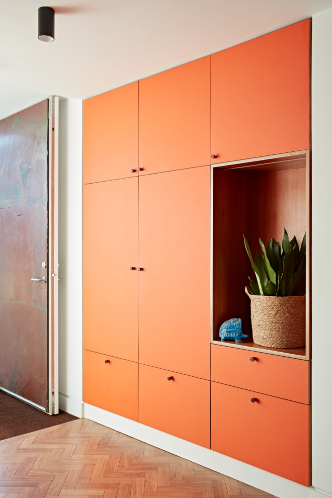 Design ideas for a mid-sized midcentury front door in Sussex with orange walls, light hardwood floors, a single front door, a metal front door, brown floor and panelled walls.