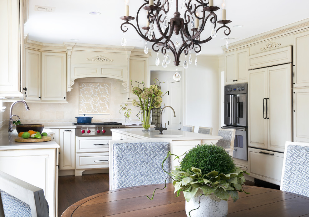 Large transitional l-shaped medium tone wood floor eat-in kitchen photo in Newark with a single-bowl sink, beige cabinets, quartzite countertops, beige backsplash, stone tile backsplash, paneled appliances, an island and raised-panel cabinets