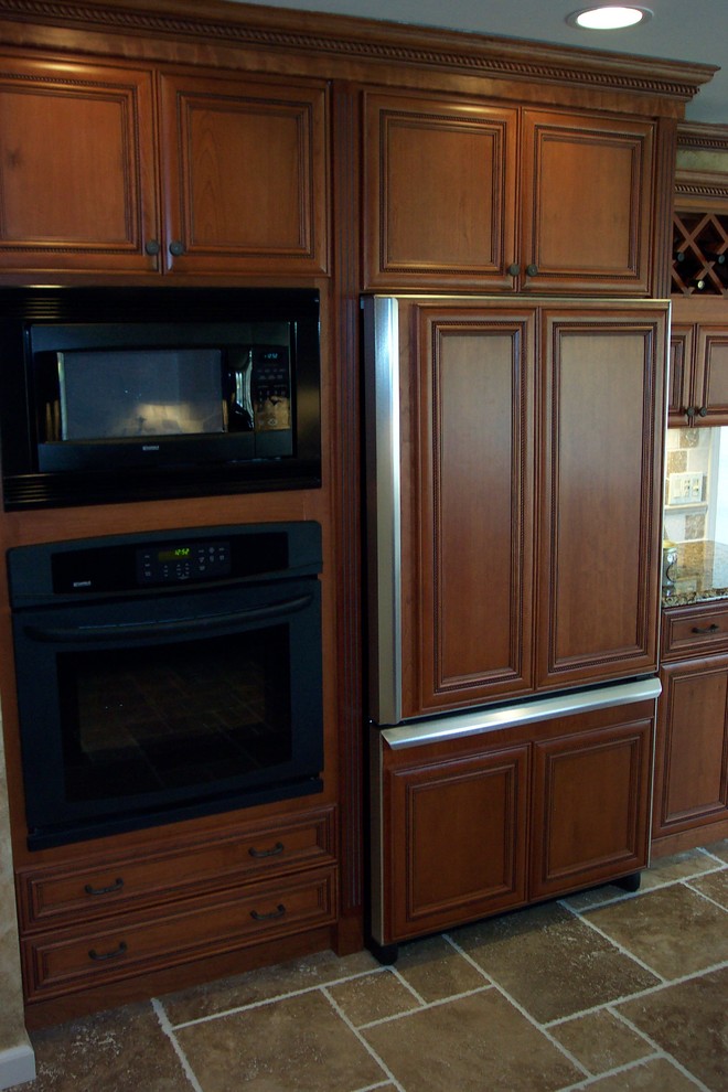 Example of a transitional l-shaped porcelain tile kitchen pantry design with a double-bowl sink, recessed-panel cabinets, medium tone wood cabinets, granite countertops, beige backsplash, stone tile backsplash, stainless steel appliances and no island