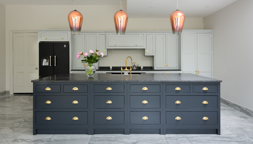 This is an example of a large traditional open plan kitchen in London with shaker cabinets, quartz benchtops, marble floors and with island.